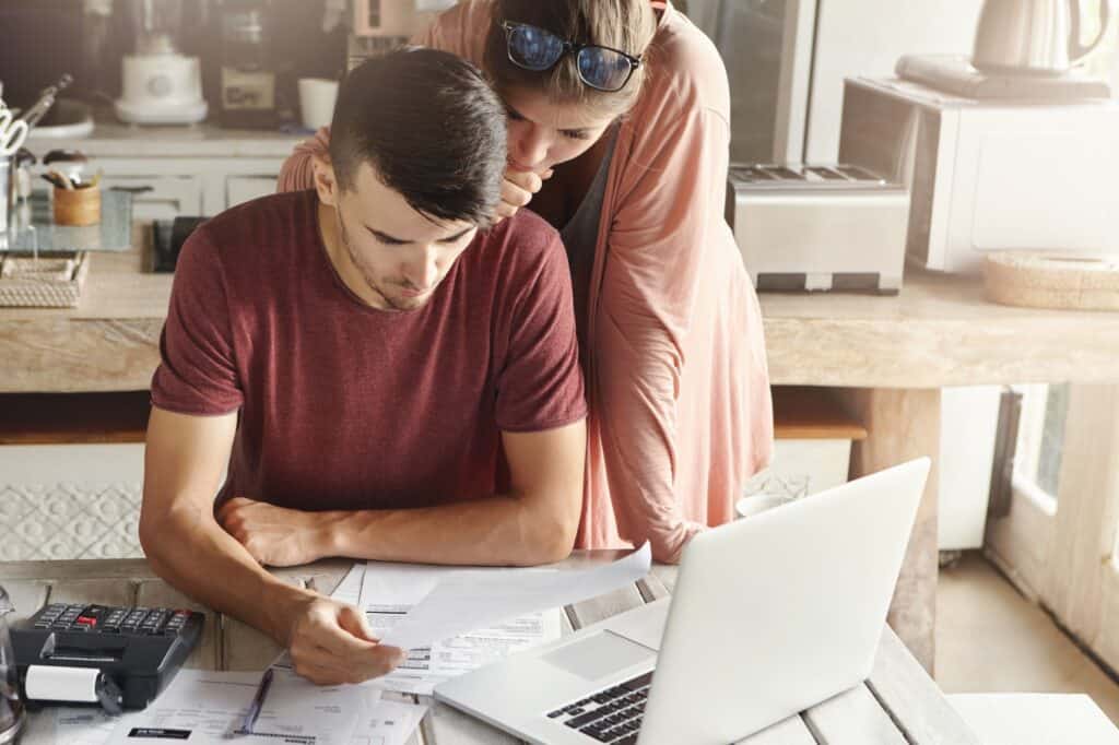 A young couple comparing quotes from multiple man-and-van companies in the concept of "How to Get a Quote for a Man and Van Service'.