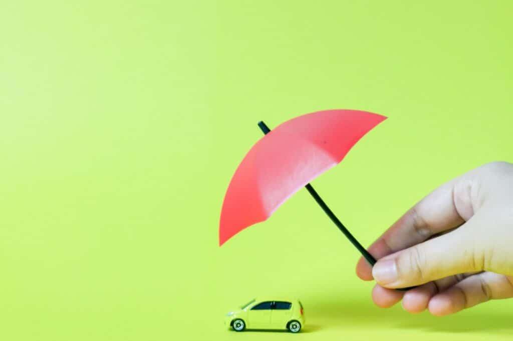 A toy van covered with an umbrella in the concept of Insurance Coverage